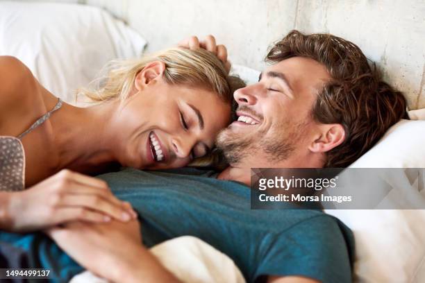 romantic young couple smiling in bed - boyfriend stockfoto's en -beelden