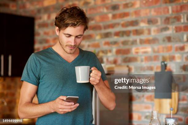 man using smart phone while holding coffee cup - handsome stock pictures, royalty-free photos & images