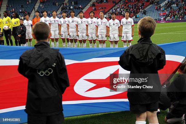 Children display the national flag of DPR Korea in front of the DPR Korea team during the Women's Football first round Group G match between France...