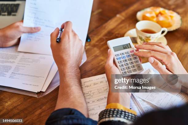 couple doing paperwork with a calculator at home - debt stock pictures, royalty-free photos & images