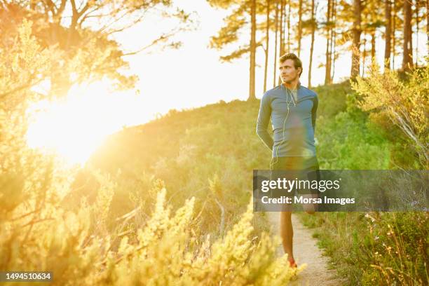 young man stretching leg before jogging on trail - quadriceps muscle stock pictures, royalty-free photos & images