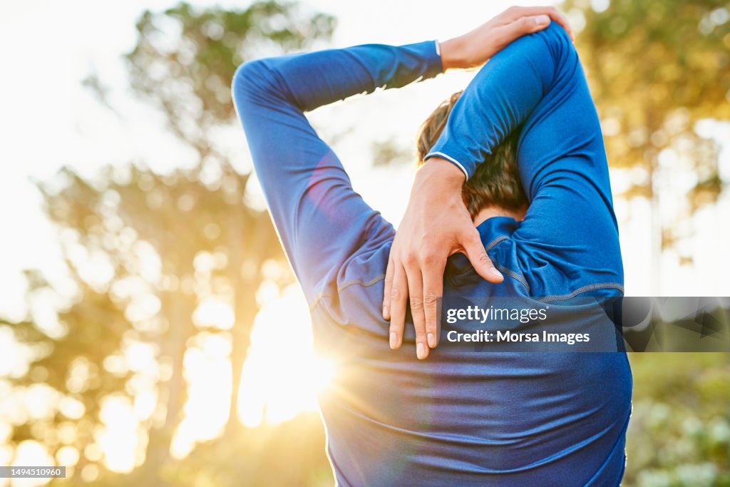 Young man stretching arm and shoulder outdoors