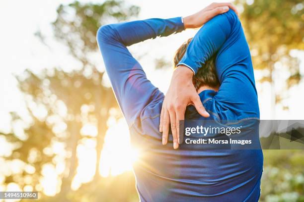 young man stretching arm and shoulder outdoors - articulation-du-corps-humain photos et images de collection