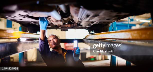 female car mechanic doing vehicle checks - car underside stock pictures, royalty-free photos & images