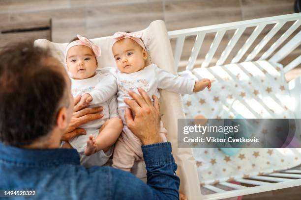 father playing with his twin baby girls in the nursery - baby wipes stock pictures, royalty-free photos & images