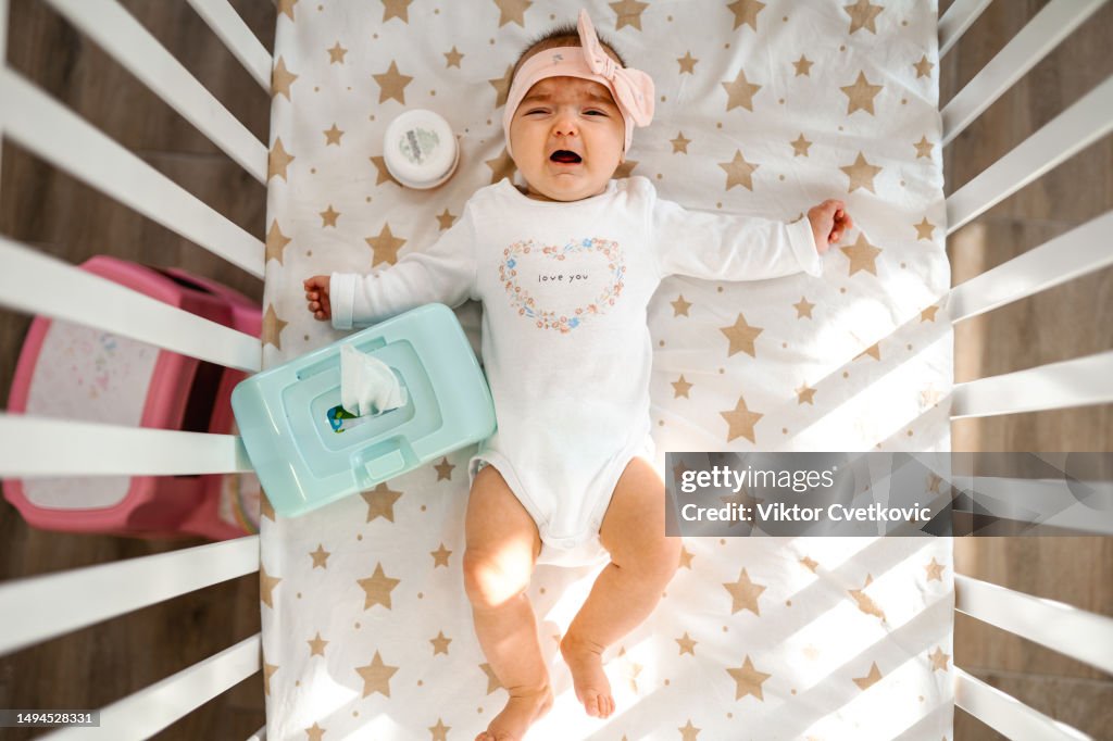 Baby girl crying in a crib