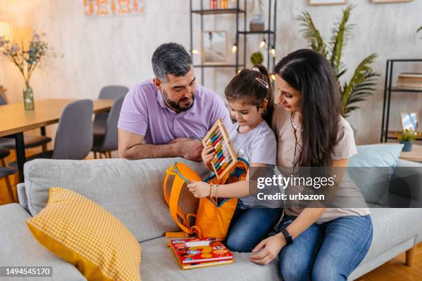 daughter packing her backpack for school with the help of her parents - back to school stock pictures, royalty-free photos & images