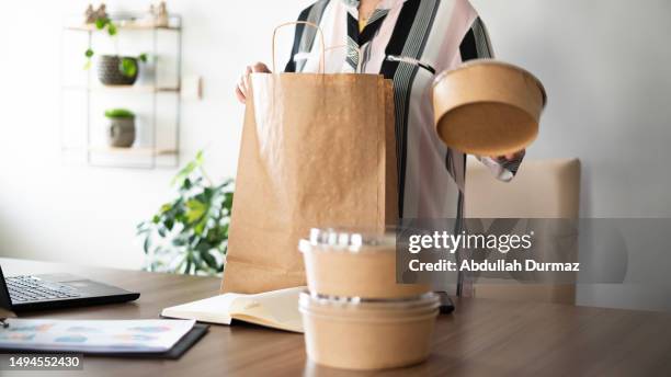 adult woman taking food order out of cardboard package - order takeout stock pictures, royalty-free photos & images