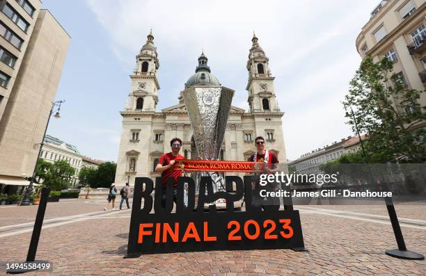 Roma supporters pose with a large replica of the UEFA Europa League trophy by St Stephen's Basilica prior to the UEFA Europa League 2022/23 final...