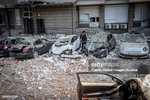 An owner stands next to his car, wrecked by the rubble of a residential building hit by a downed kamikaze drone on May 30, 2023 in Kyiv, Ukraine....
