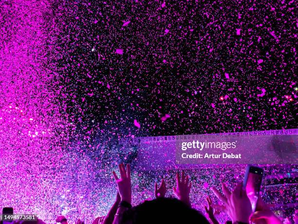 dancing in a concert with confetti and crowd of people with energy. - concierto fotografías e imágenes de stock