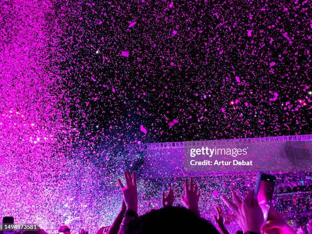 dancing in a concert with confetti and crowd of people with energy. - stadium concert stock pictures, royalty-free photos & images