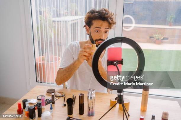 young man doing a live about how to do makeup - tripod stock-fotos und bilder
