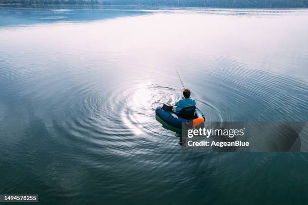 aerial view of man fishing from inflatable boat - fishing rod stock pictures, royalty-free photos & images