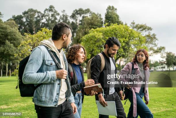 student friends talking while walking through the university campus - group of people walking stock pictures, royalty-free photos & images