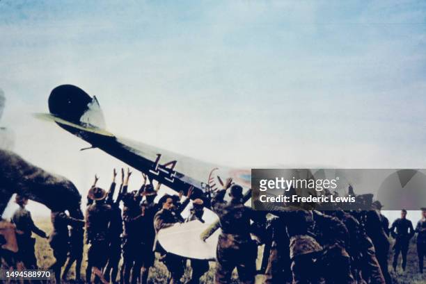 Soldiers lift an upended Nieuport 28 fighter plane back onto its wheels, circa 1918.