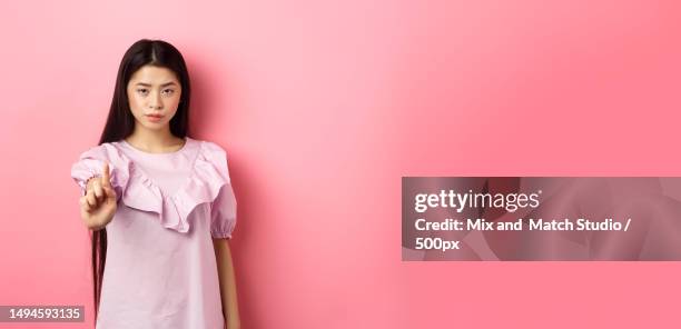 she says no serious asian girl shaking finger in stop gesture - shaking finger stock pictures, royalty-free photos & images