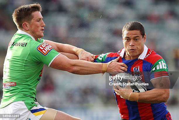 Timana Tahu of the Knights fends off Josh McCrone of the Raiders during the round 21 NRL match between the Canberra Raiders and the Newcastle Knights...