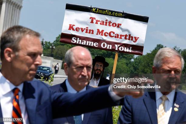 With a demonstrator standing in the background, House Freedom Caucus members Chair Rep. Scott Perry , Rep. Dan Bishop and Rep. Ralph Norman talk to...