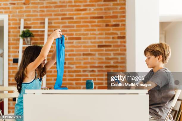 niños sentados a la mesa y jugando con limo - limoso fotografías e imágenes de stock