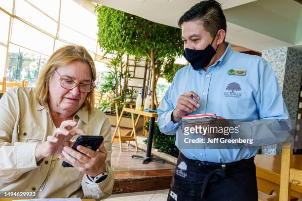 Mexico City, Mexico, Del Bosque Restaurante, waiter taking order, customer using smartphone to read digital e-menu.