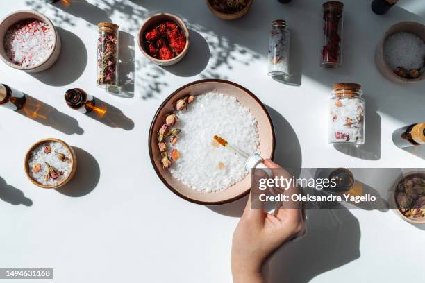 concept of spa and wellness. fresh aromatic bath salt with rose petals. rose extract or oil. woman's hand with a pipette - bath salt ストックフォトと画像