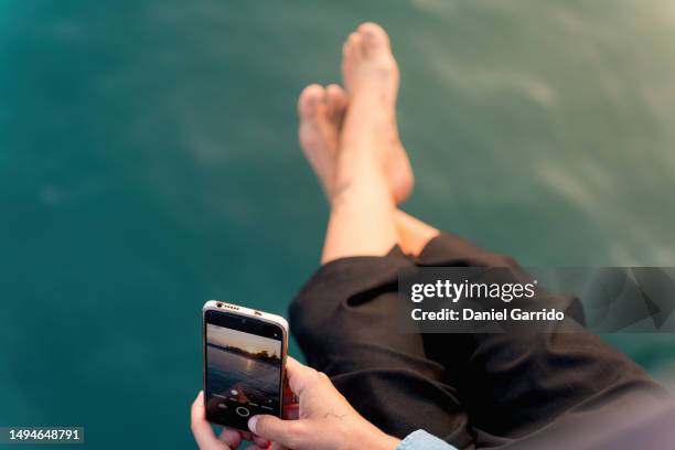 creative hands immortalizing the beauty of bare feet and the sea, beach selfie, the bare feet of the girl as protagonists alongside the sea - womans bare feet fotografías e imágenes de stock