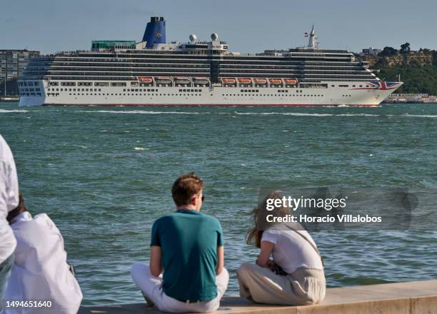 May 30: Tourists relax atop the waterline at the Quiosque da Ribeira das Naus as MS Arcadia, a 84,342 GT cruise ship in the P&O Cruises fleet, sails...