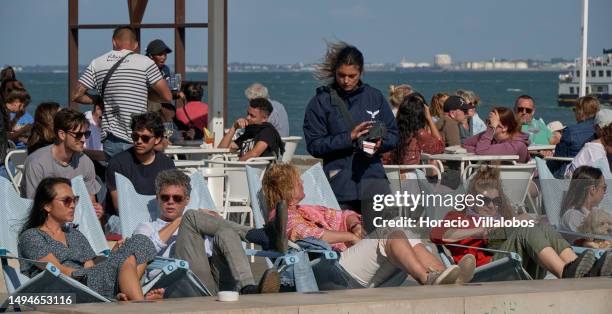 May 30: A waitress takes orders from tourists relaxing at Quiosque da Ribeira das Naus by the Tagus River on a sunny afternoon on May 30, 2023 in...