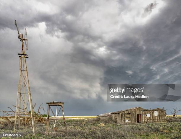 old abandoned structures and windmill on the great plains with impending storms - impending stock pictures, royalty-free photos & images