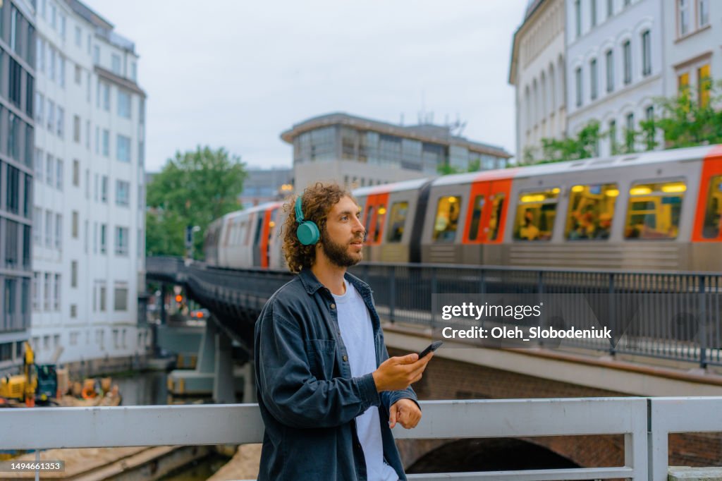 Man listening to music in headphones on the background of subway in Hamburg