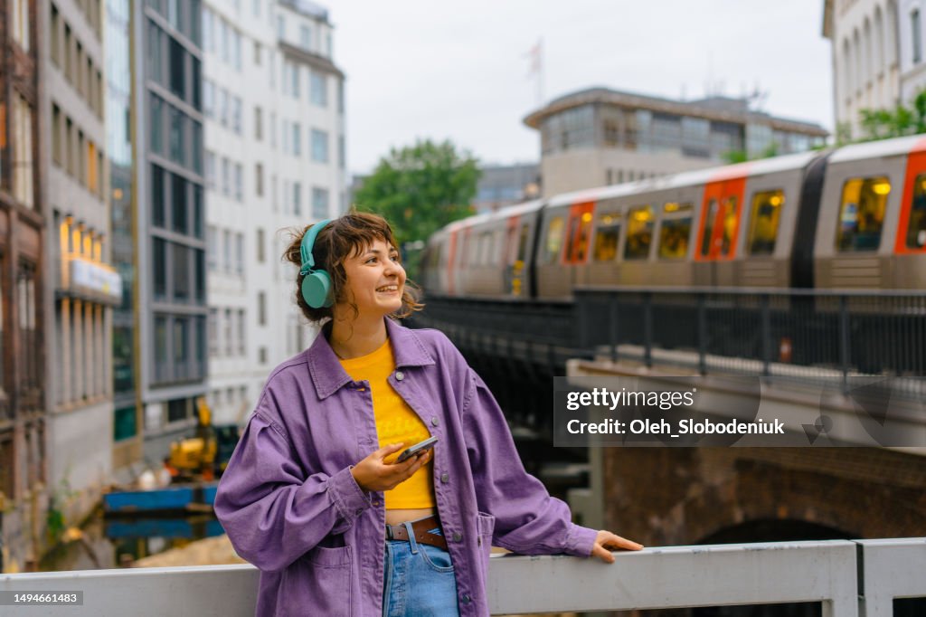 Frau hört Musik über Kopfhörer im Hintergrund der Hamburger U-Bahn