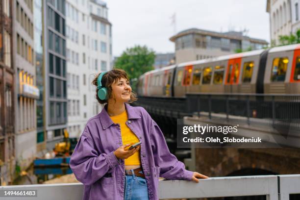 frau hört musik über kopfhörer im hintergrund der hamburger u-bahn - kopfhörer stock-fotos und bilder