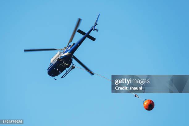 helicopter flies with water bucket - buckets stock pictures, royalty-free photos & images