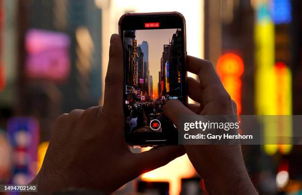 Person stands on 42nd Street in Times Square as he photographs the second evening of the Manhattanhenge sunset on May 30 in New York City.