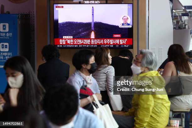 People watch a television broadcast showing a file image of a North Korean rocket launch at the Seoul Railway Station on May 31, 2023 in Seoul, South...