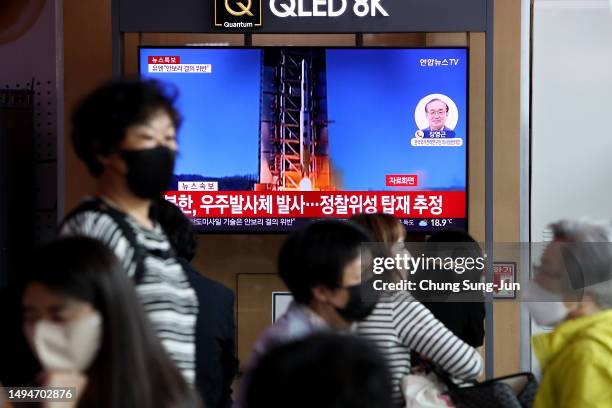 People watch a television broadcast showing a file image of a North Korean rocket launch at the Seoul Railway Station on May 31, 2023 in Seoul, South...