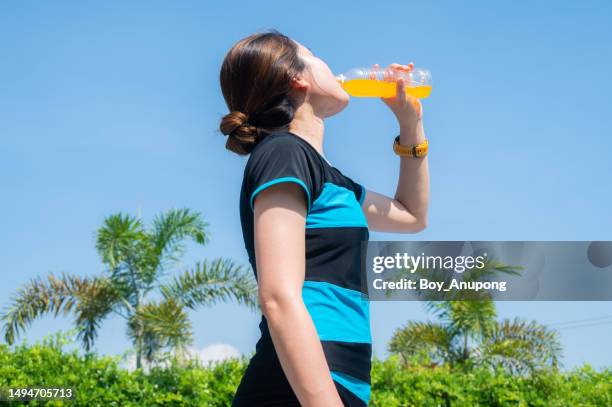 asian woman while drinking an energy drink after doing outdoor workout. energy drinks may enhance alertness and improve reaction time. - energydrink stock-fotos und bilder