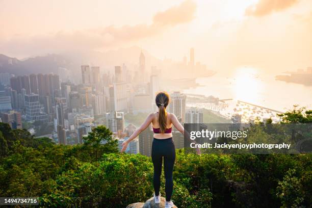 a young woman watches the sunset over hong kong. - young woman standing against clear sky ストックフォトと画像