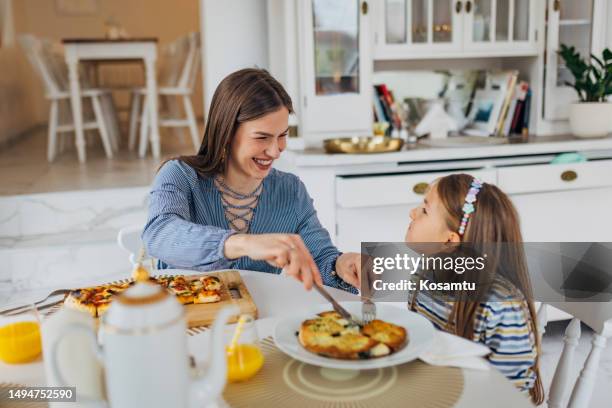 a little girl is enjoying lunch in a restaurant with her mother. they eat their favorite food, pizza and tortillas - eating pesto stock pictures, royalty-free photos & images