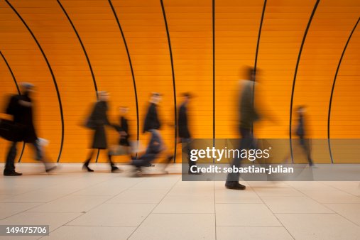 Große Gruppe von Menschen vor modernen orange U-Bahn-Röhre Große Gruppe von Menschen vor modernen orange U-Bahn-Röhre