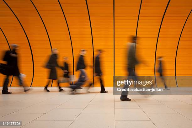 grande gruppo di persone contro arancio moderno tubo della metropolitana - esposizione lunga foto e immagini stock