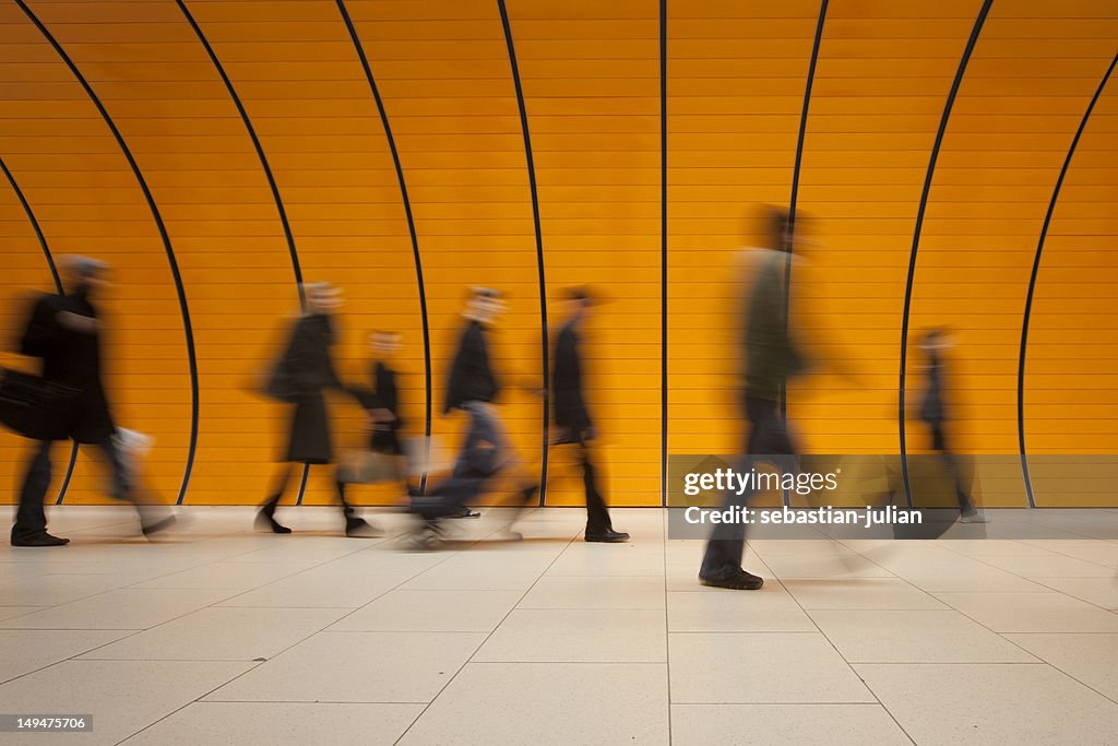Large group of people against modern orange subway tube