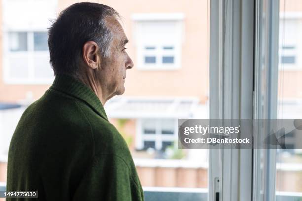 senior man with alzheimer's and depression, sideways, looking out the window. concept of old age, disease, loneliness, forgetfulness and memory. - cuenca característica de la tierra fotografías e imágenes de stock