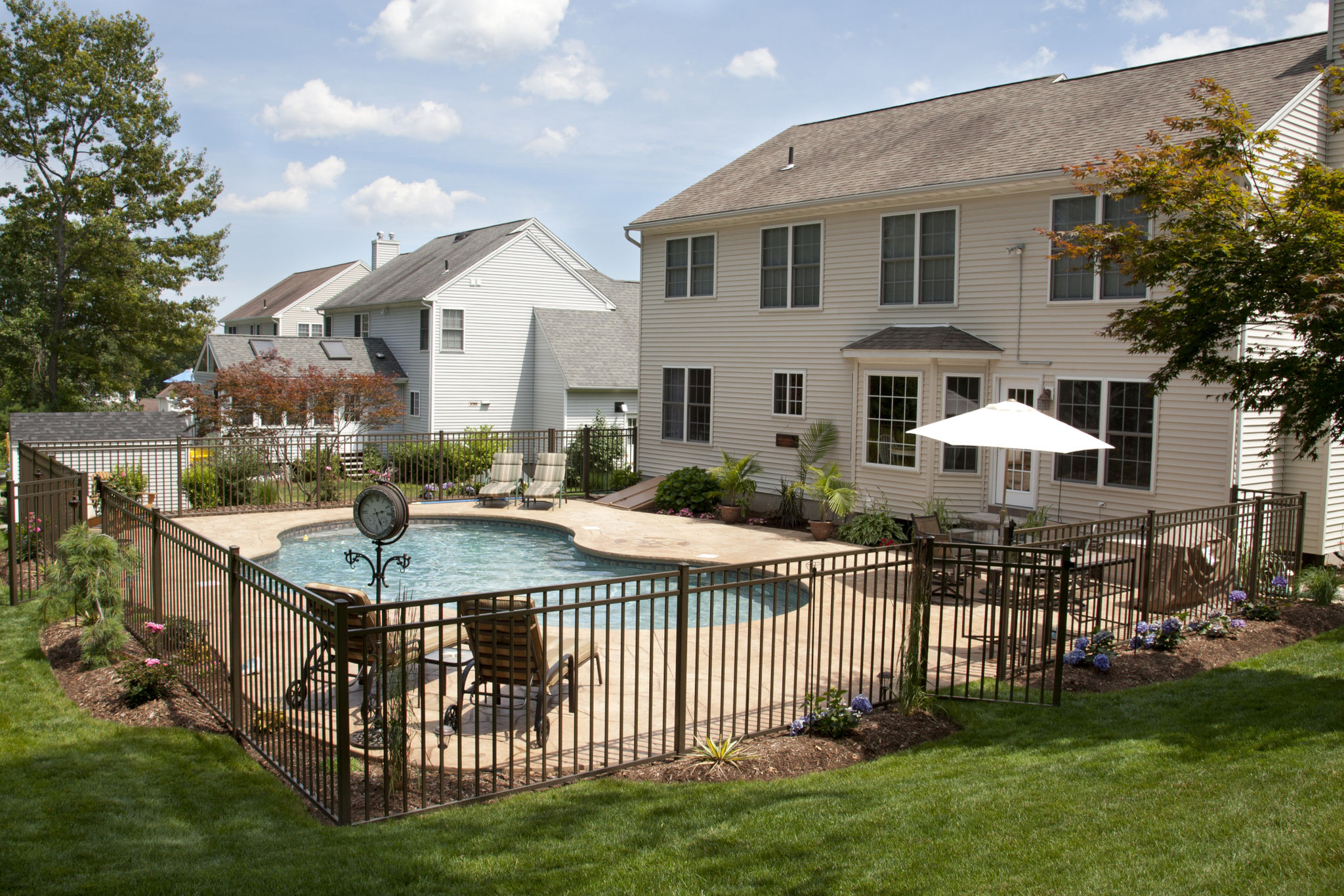 Lush backyard pool and patio behind colonial style home. Lush backyard pool and patio behind colonial style home.