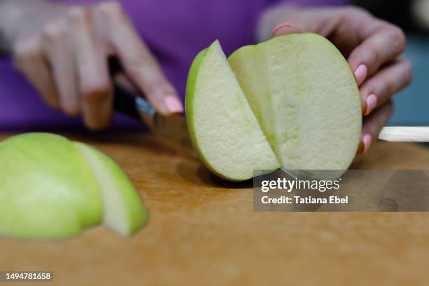 woman cutting green apple in the kitchen - cutting green apple stock pictures, royalty-free photos & images