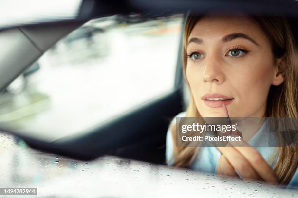 quickly refreshing her makeup - woman lipstick rearview stock pictures, royalty-free photos & images