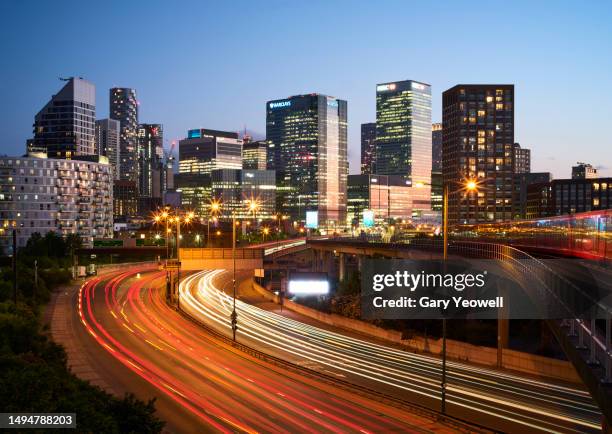 london canary wharf skyline by busy road network at dusk - vehicle light stock pictures, royalty-free photos & images