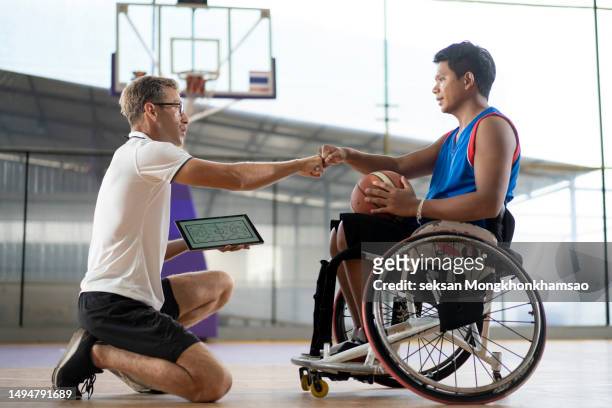 coach and male wheelchair basketball player doing fist bump together. - people showing respect stock pictures, royalty-free photos & images