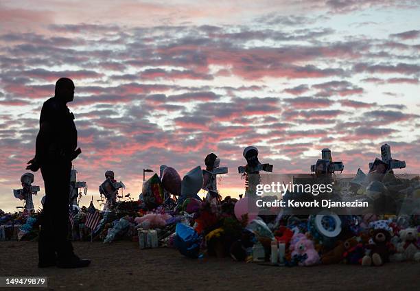 An Aurora, Colorado Police officer visits the roadside memorial set up for victims of the theaters shooting massacre across the street from Century...